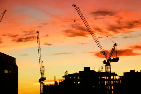 Cranes on an industrial construction site at sunset